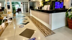 A hotel reception area with a modern design, including a reception desk, seating area, and a view of the outdoors. - HOTEL EUROASIA (Angeles City)