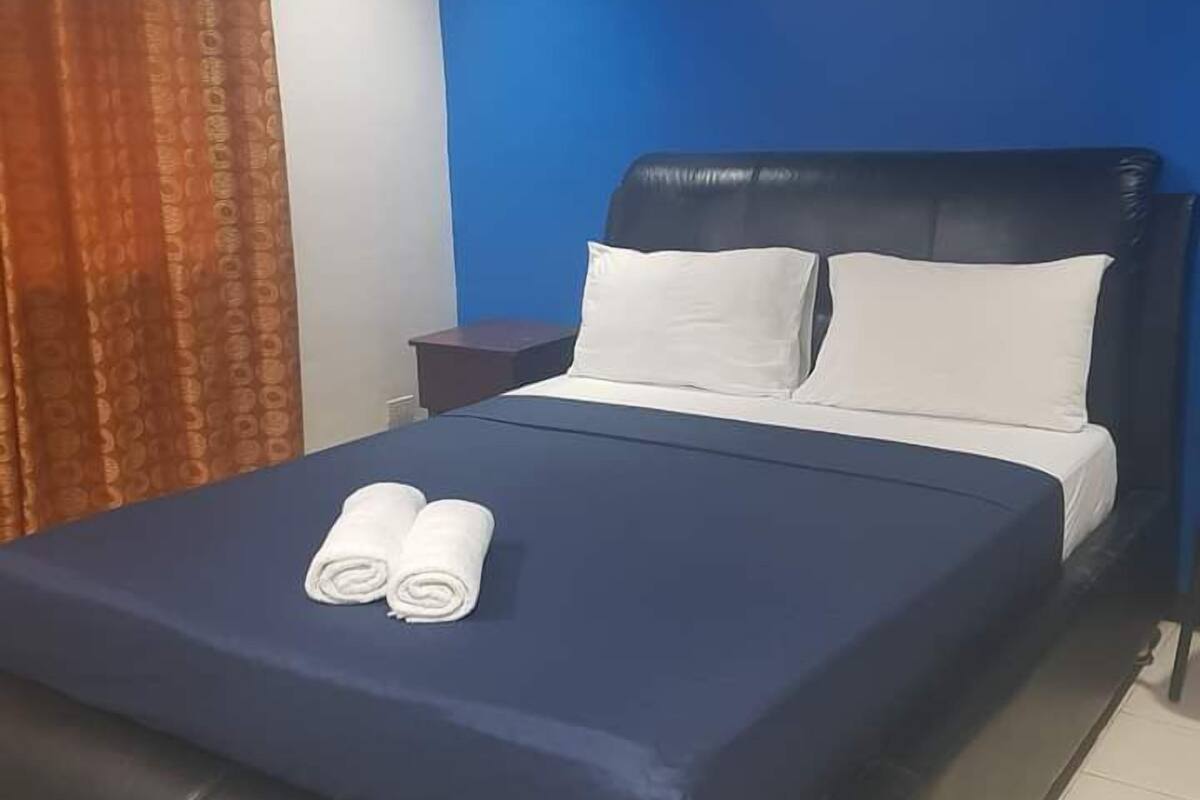 Quarto de hotel com cama, mesa de cabeceira e cortina.