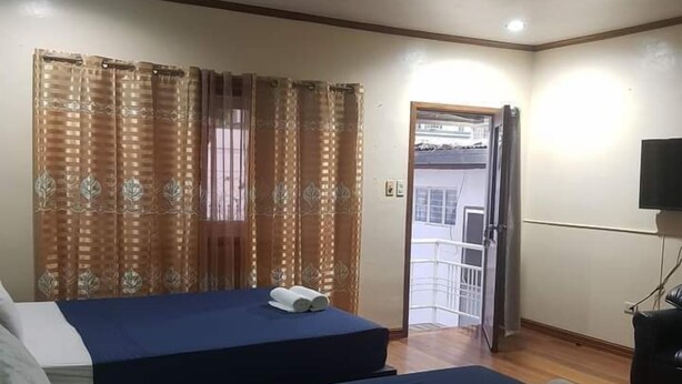 A hotel room with two beds, a television, and a door leading to a balcony. - Platinum Hotel (Angeles City)