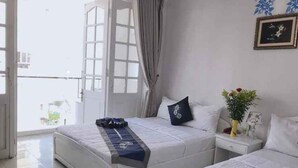 A bedroom with two beds, a nightstand, a window with curtains, and a framed picture on the wall.