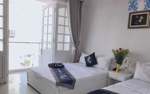 A hotel room with two beds, a nightstand, a window with curtains, and a framed picture on the wall. - Ximao Hotel Nha Trang by Zuzu (Nha Trang)