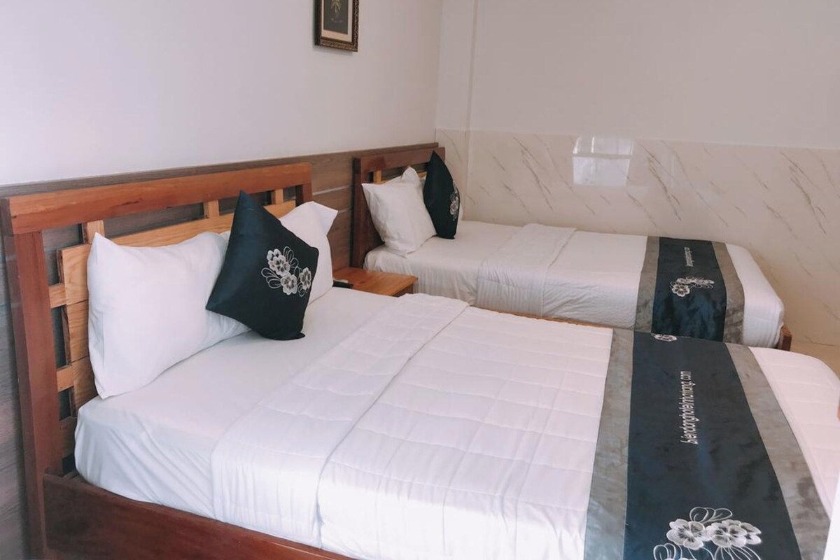 Two single beds with wooden headboards, white bedding, and black decorative pillows.