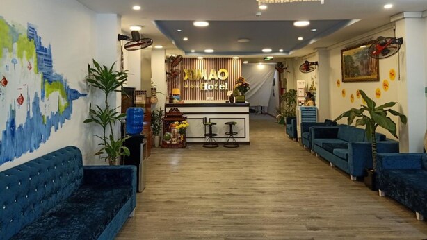 A hotel lobby with a reception desk, blue sofas, a chandelier, and a mural on the wall.