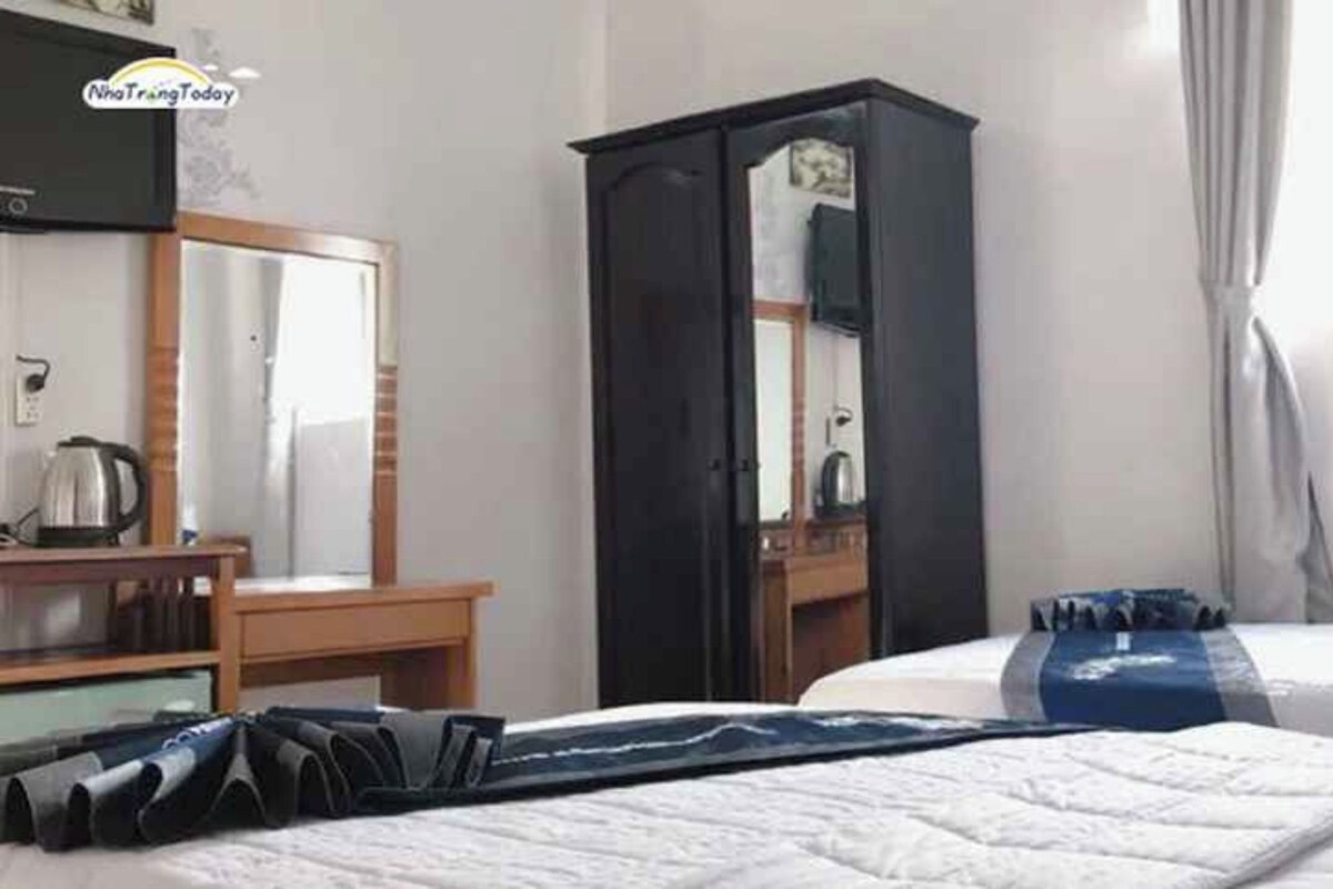 A hotel room with a bed, a desk, a wardrobe, and a mirror.