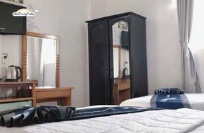 A hotel room with a bed, a desk, a wardrobe, and a mirror. - Ximao Hotel Nha Trang by Zuzu (Nha Trang)