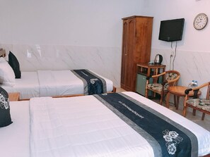 A hotel room with two beds, a wooden wardrobe, a television, and a small table with chairs. - Ximao Hotel Nha Trang by Zuzu (Nha Trang)