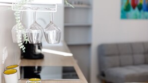 A kitchen counter with hanging wine glasses, a coffee machine, and a tablet.