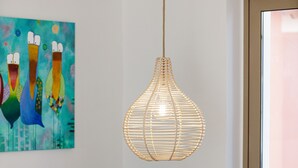 A modern living room with a grey sofa, patterned cushions, a white coffee table, and a unique woven pendant light.