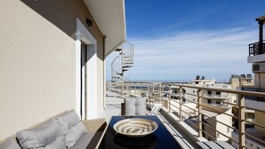 A balcony with a sofa, a woven tray, and a view of the cityscape.