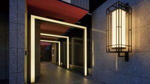 Exterior de un edificio moderno con un sendero, un alero rojo y una lámpara fijada a la pared.