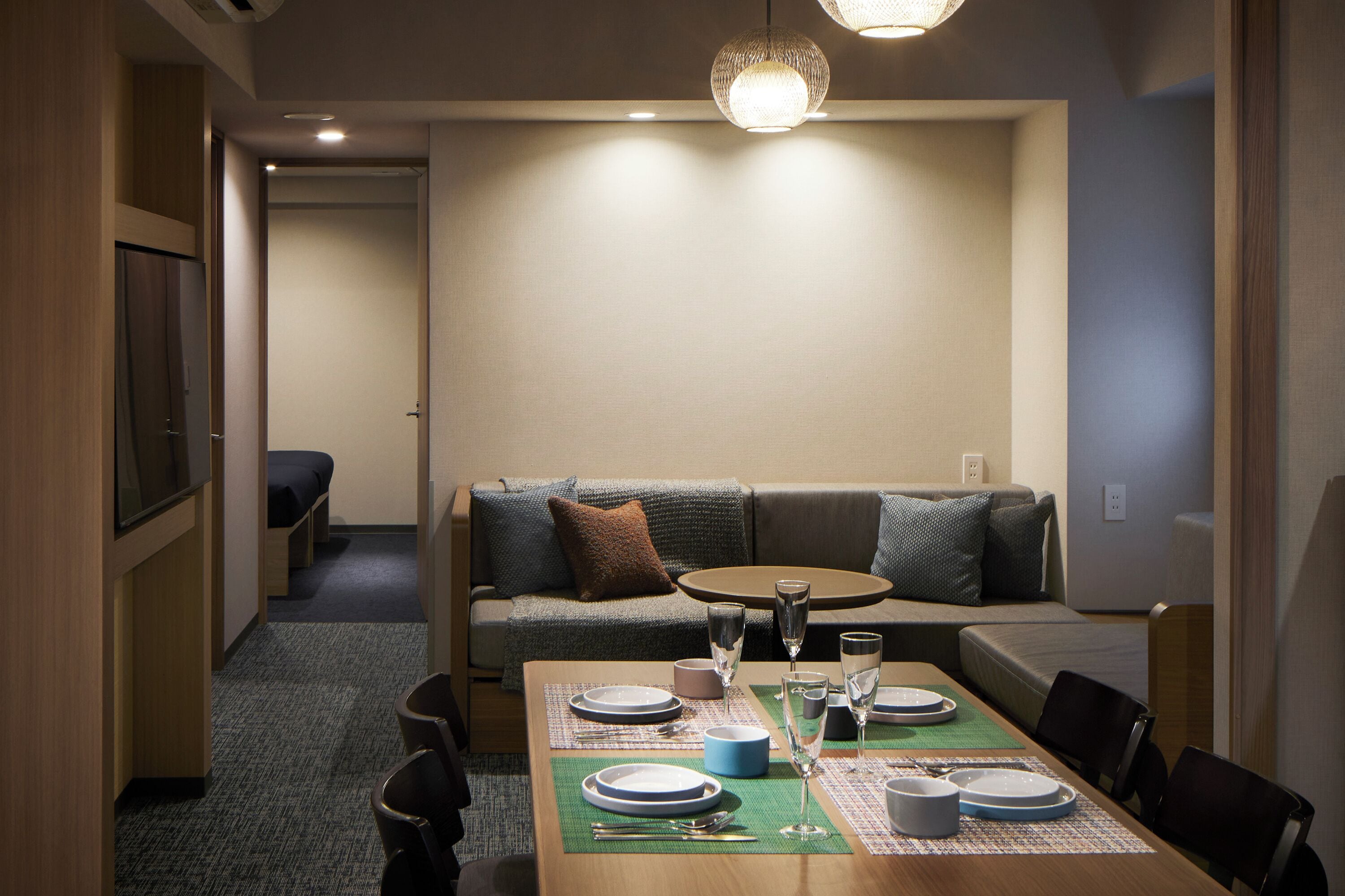 Un comedor con una mesa preparada para cuatro personas, un sofá y una mesita redonda.