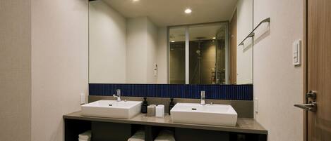 A modern bathroom with two sinks, a large mirror, and shelves with folded towels.