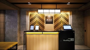 Un mostrador de recepción con acabado de madera, dos monitores de computadora y un cartel que dice "Minn your second home".