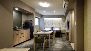 Una habitación de hotel compacta con kitchenette, comedor y cama.