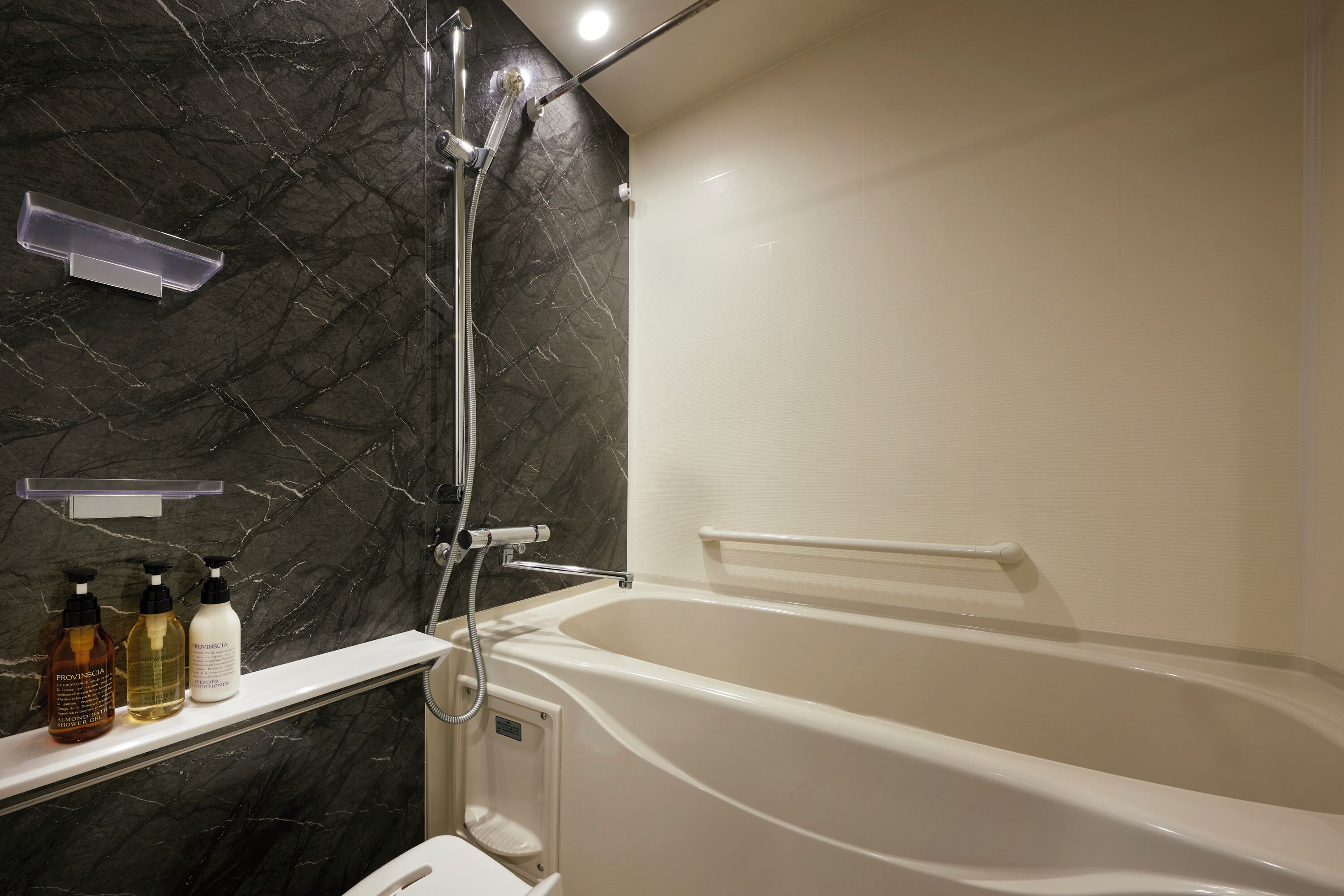 A modern bathroom with a freestanding bathtub, a showerhead, and a marble wall.