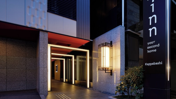 Una entrada de edificio moderno con un letrero que dice "Minn your second home Kappabashi".