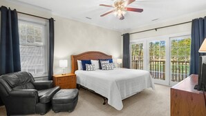 Une chambre à coucher comprenant un lit, une chaise, une table de chevet, un bureau et un ventilateur de plafond.
