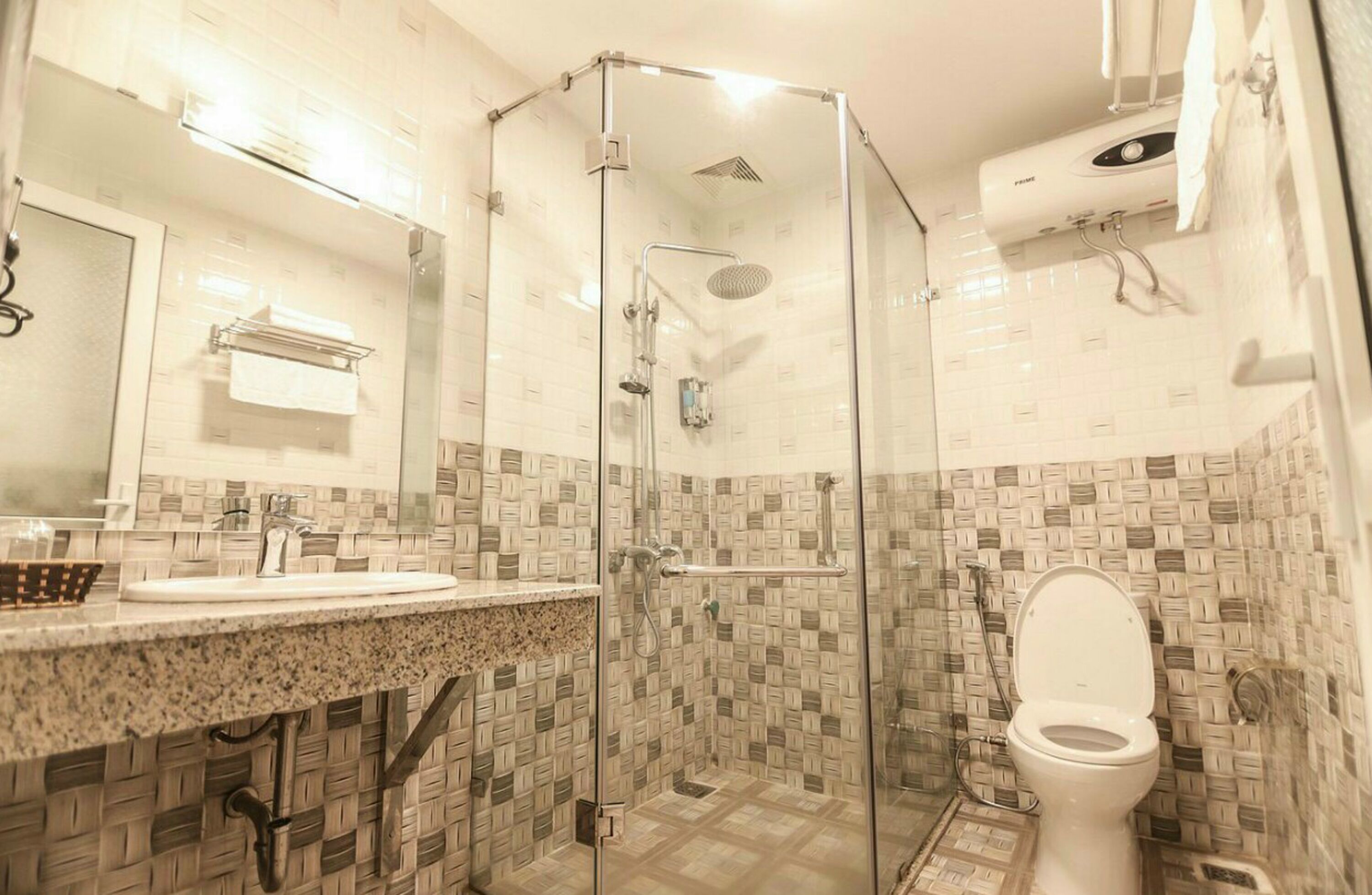 A bathroom with a glass-enclosed shower, a sink with a granite countertop, and a toilet.