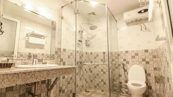 A bathroom with a glass-enclosed shower, a sink with a granite countertop, and a toilet.