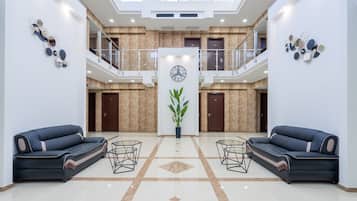 Relax in our spacious lobby, featuring a high ceiling, comfortable seating, and a touch of greenery.