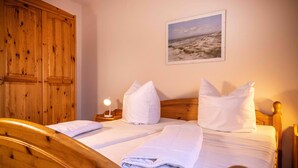 Une chambre à coucher avec un lit en bois, une literie blanche et une table de chevet avec une lampe.