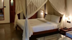 A bedroom with a four-poster bed, a glass coffee table, and a wooden chair. - The Orchard Resort (Belagavi)