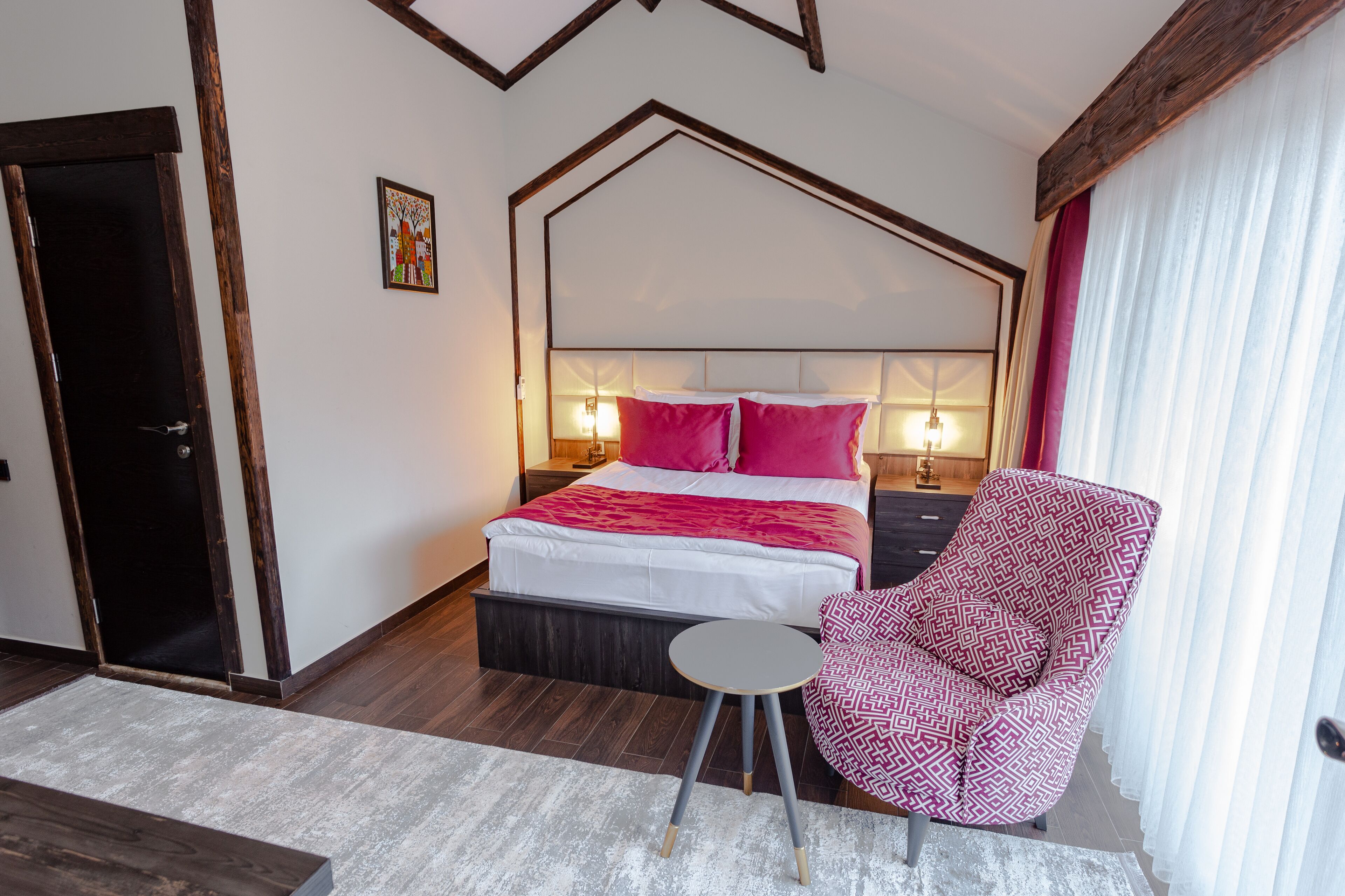 A bedroom with a four-poster bed, a nightstand, a chair, and a door.