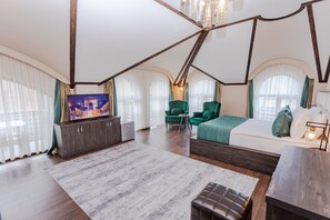Ein geräumiges Schlafzimmer mit einem großen Bett, einem Fernseher und einer Sitzecke mit Tisch und Stühlen.