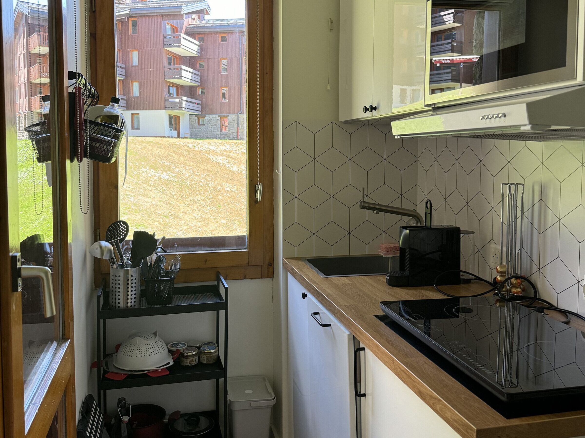 A compact kitchen with a window view, a microwave, a sink, and a stove.