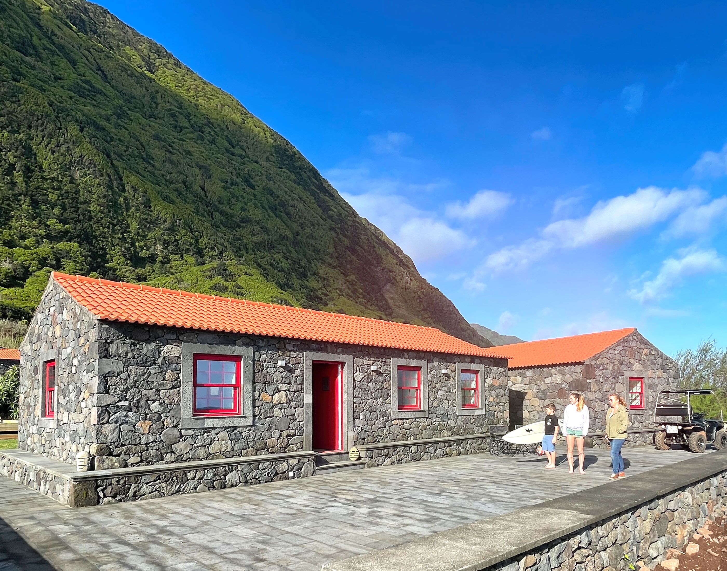 A stone building with red-tiled roofs and a stone pathway leading to it.