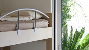 Ein Stockbett mit Holzrahmen und eine Schiebetür zu einem Garten mit Pflanzen.