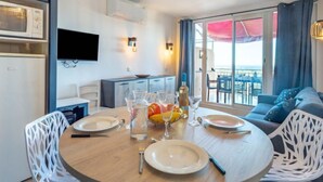 A modern dining area with a round table set for four, white chairs, and a view of the balcony with outdoor seating. - Les Restanques Golfe Saint Tropez by Interhome (Grimaud)