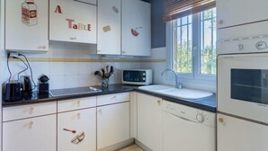 Een keuken met witte kastjes, een magnetron, een spoelbak en een fornuis.