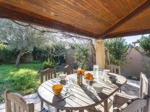 Une table ronde en bois, entourée de chaises, avec une bouteille, des verres et un panier de pain.