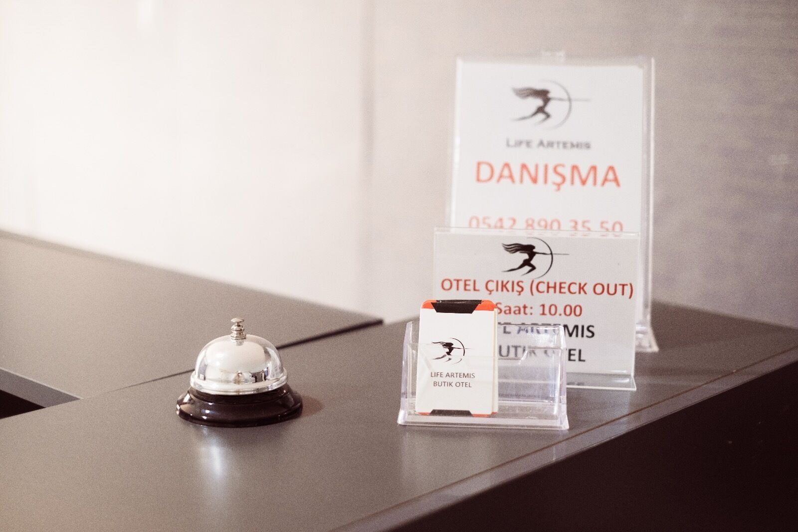A reception desk with a service bell and a check-out sign.