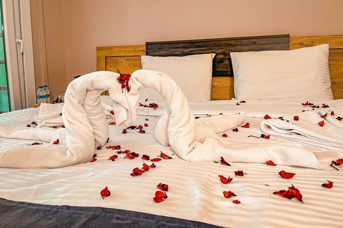 Una cama con sábanas blancas, cabecero de madera y almohadas.