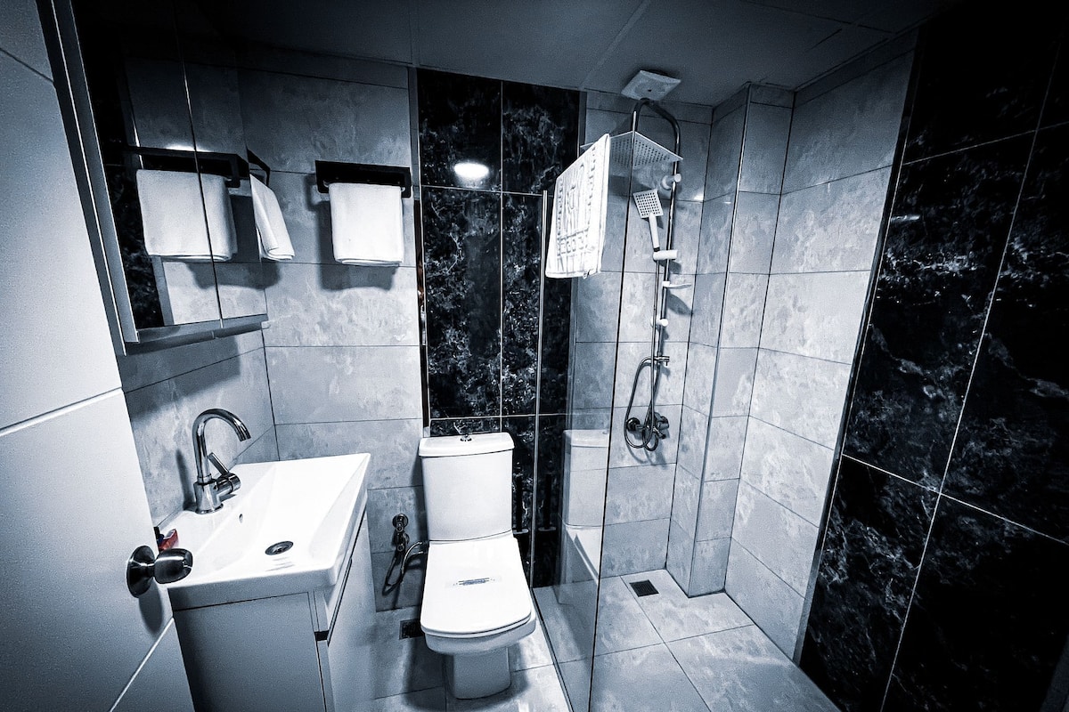 Un baño moderno con inodoro, lavamanos y ducha.