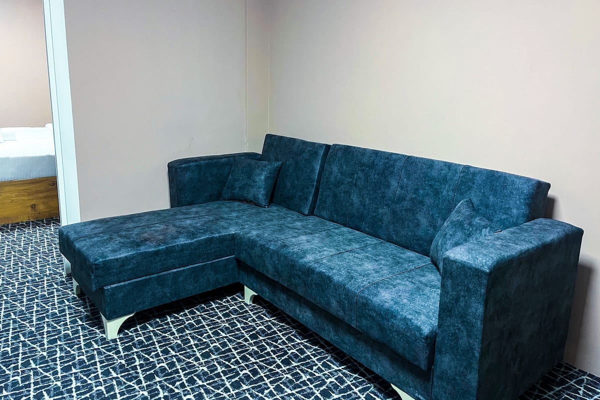 Un sofá azul modular en una esquina de la habitación, con un suelo estampado.