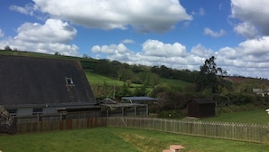 A rural property with a large barn, a fenced yard, and rolling hills in the background. - Cosy Thatched Coastal Retreat, close to Maidencombe beach & beautiful pubs. (Stokeinteignhead Torquay)