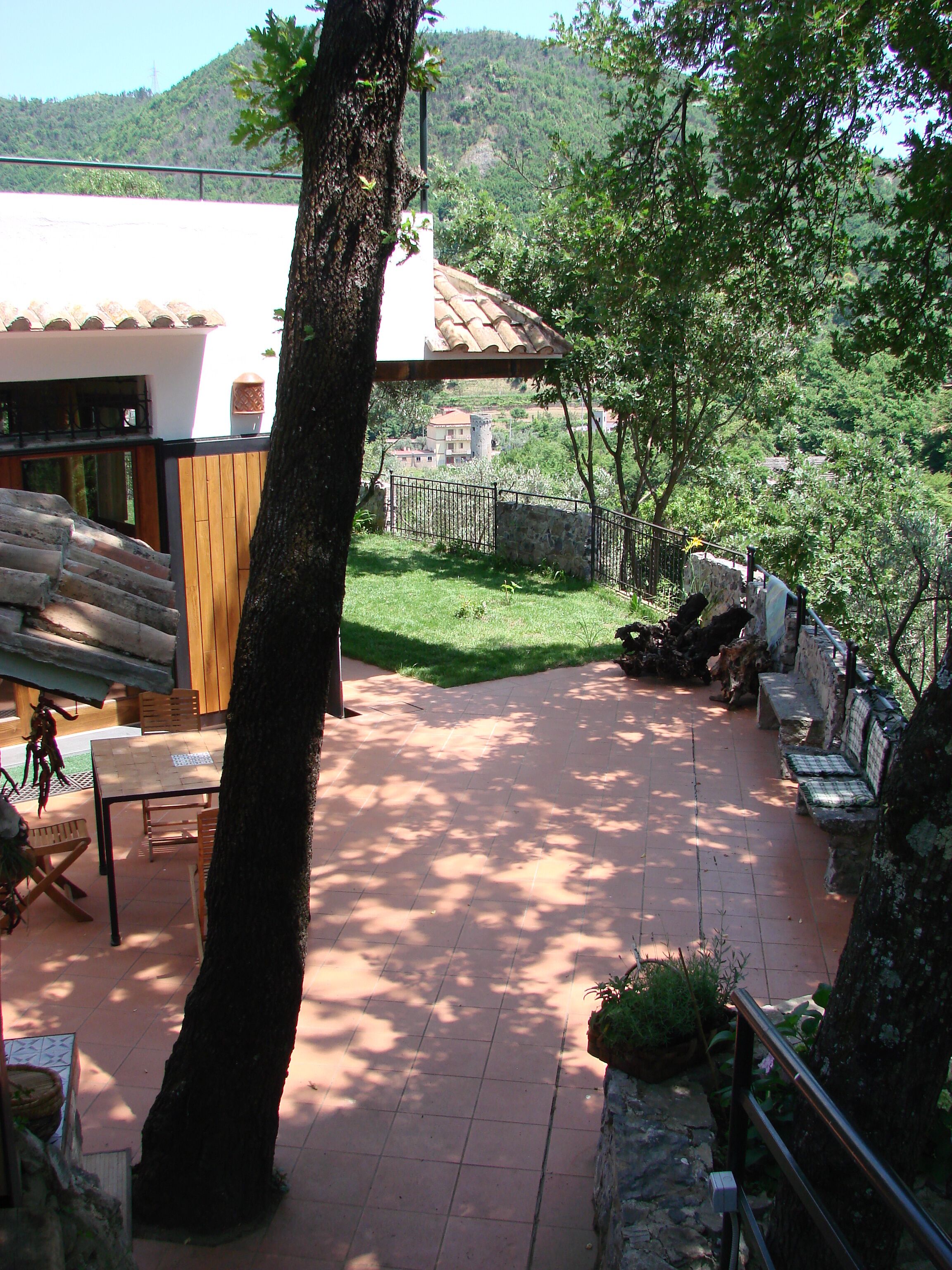 A patio area with a tiled floor, wooden furniture, and stone walls.
