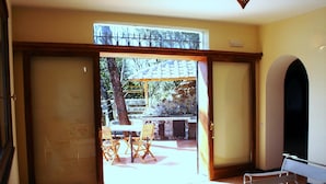 A room with a sliding door leading to an outdoor patio area with a stone fireplace and a wooden table and chairs.