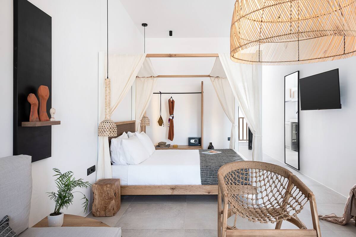 A modern bedroom with a bed, bedside table, and a wicker chair.