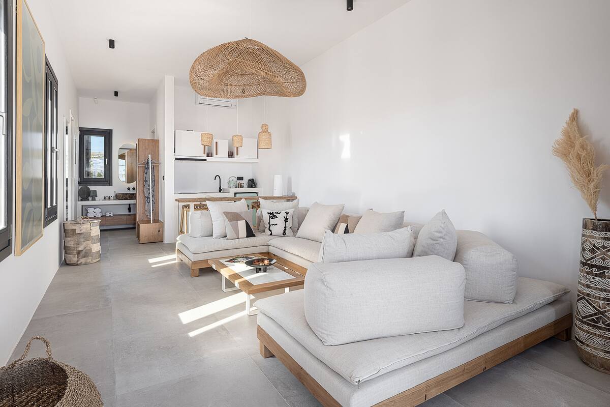 A modern living room with a sectional sofa, a coffee table, and a hanging rattan light fixture.