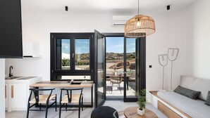 A modern kitchen with a dining area, a sofa, and a view of the outdoors.