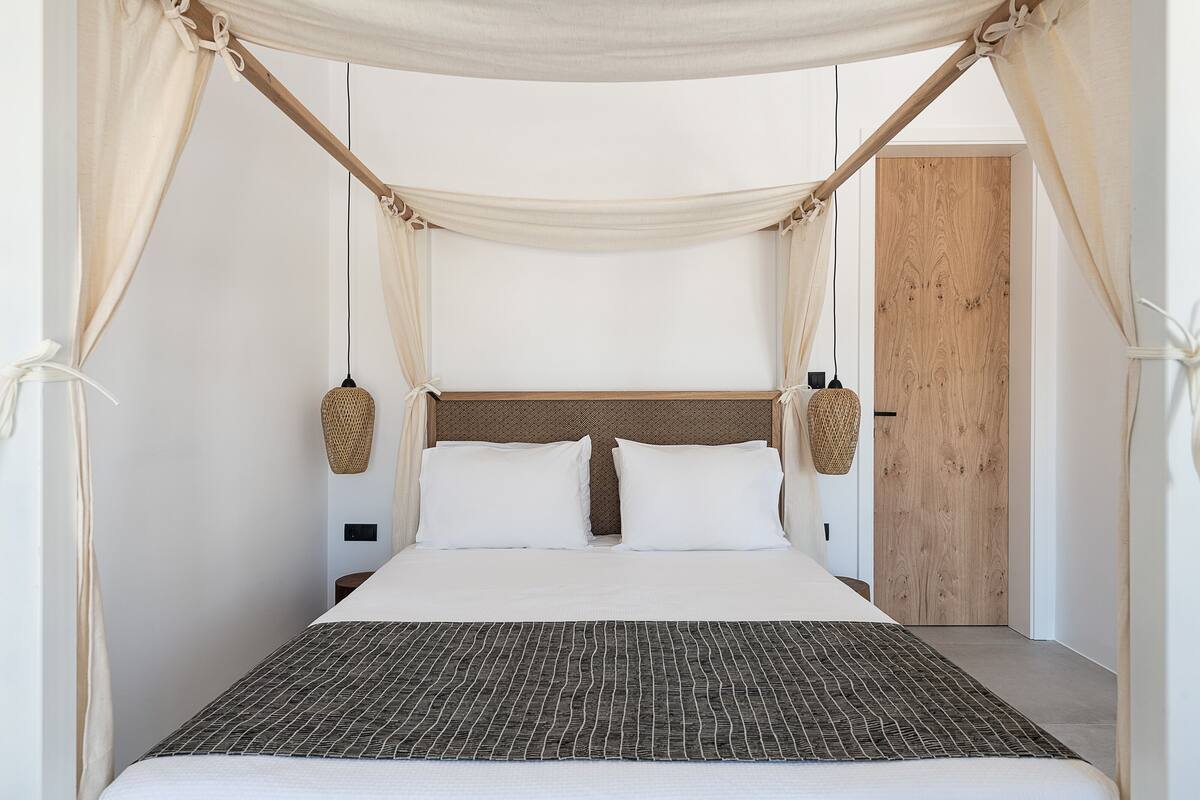 A bed with a canopy, white bedding, and a patterned throw.