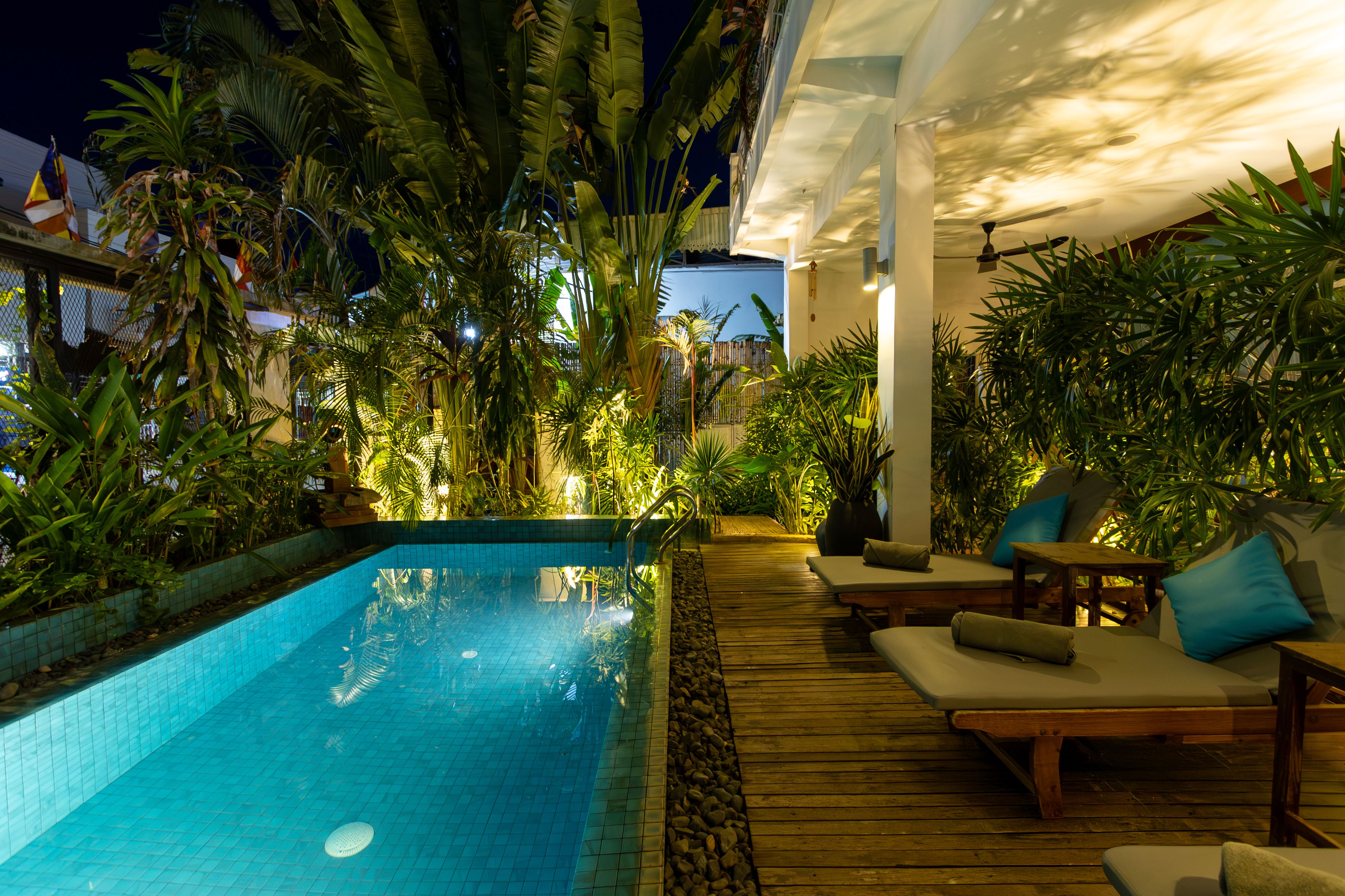 An outdoor swimming pool area with lounge chairs and a wooden deck.