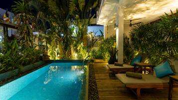An outdoor swimming pool area with lounge chairs and a wooden deck.