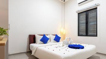 Ein Hotelzimmer mit Bett, Nachttisch, Wand-Klimaanlage und einem Fenster mit Jalousien.