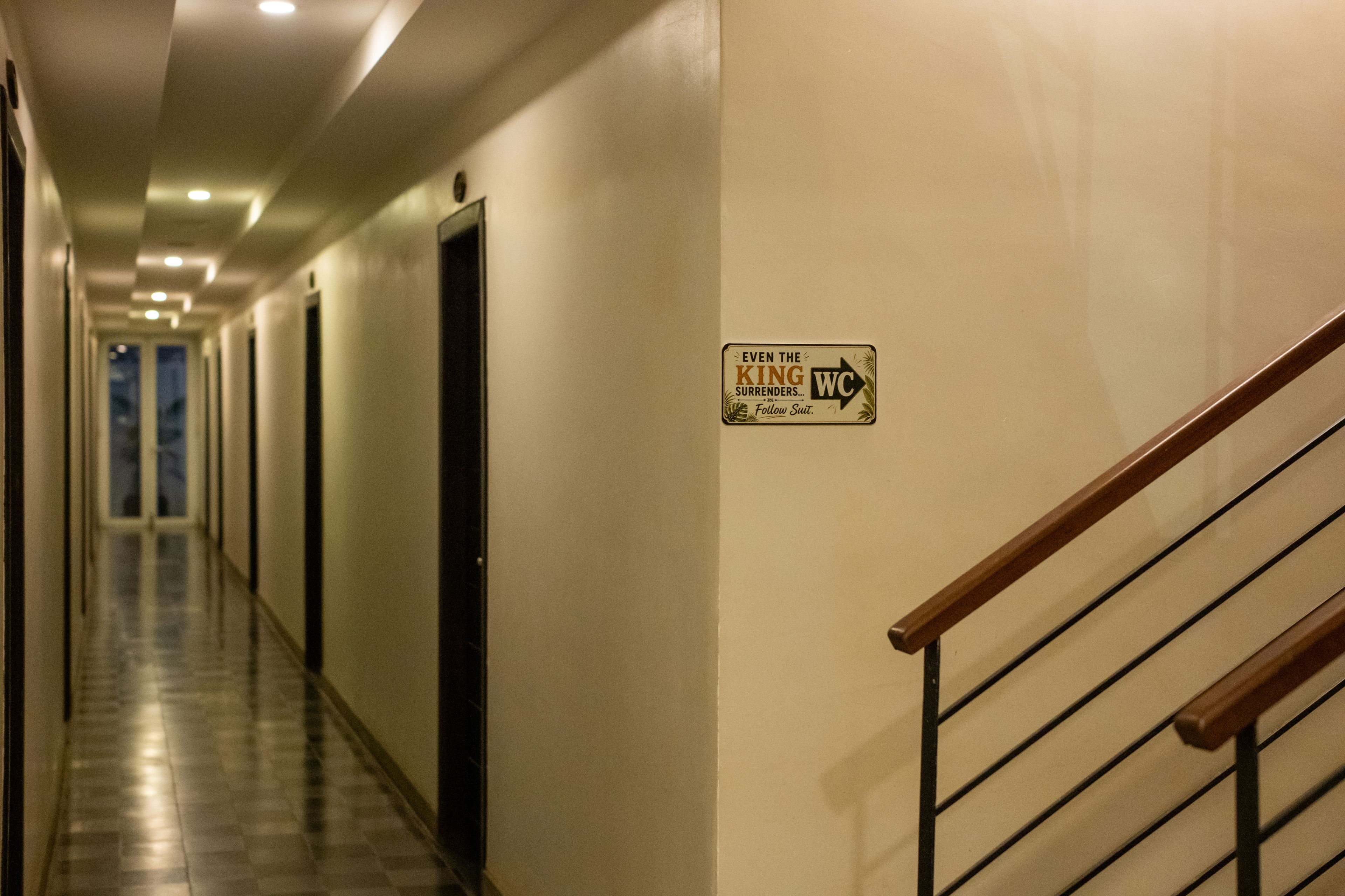 Un couloir d’hôtel avec une pancarte au mur indiquant la direction des toilettes.