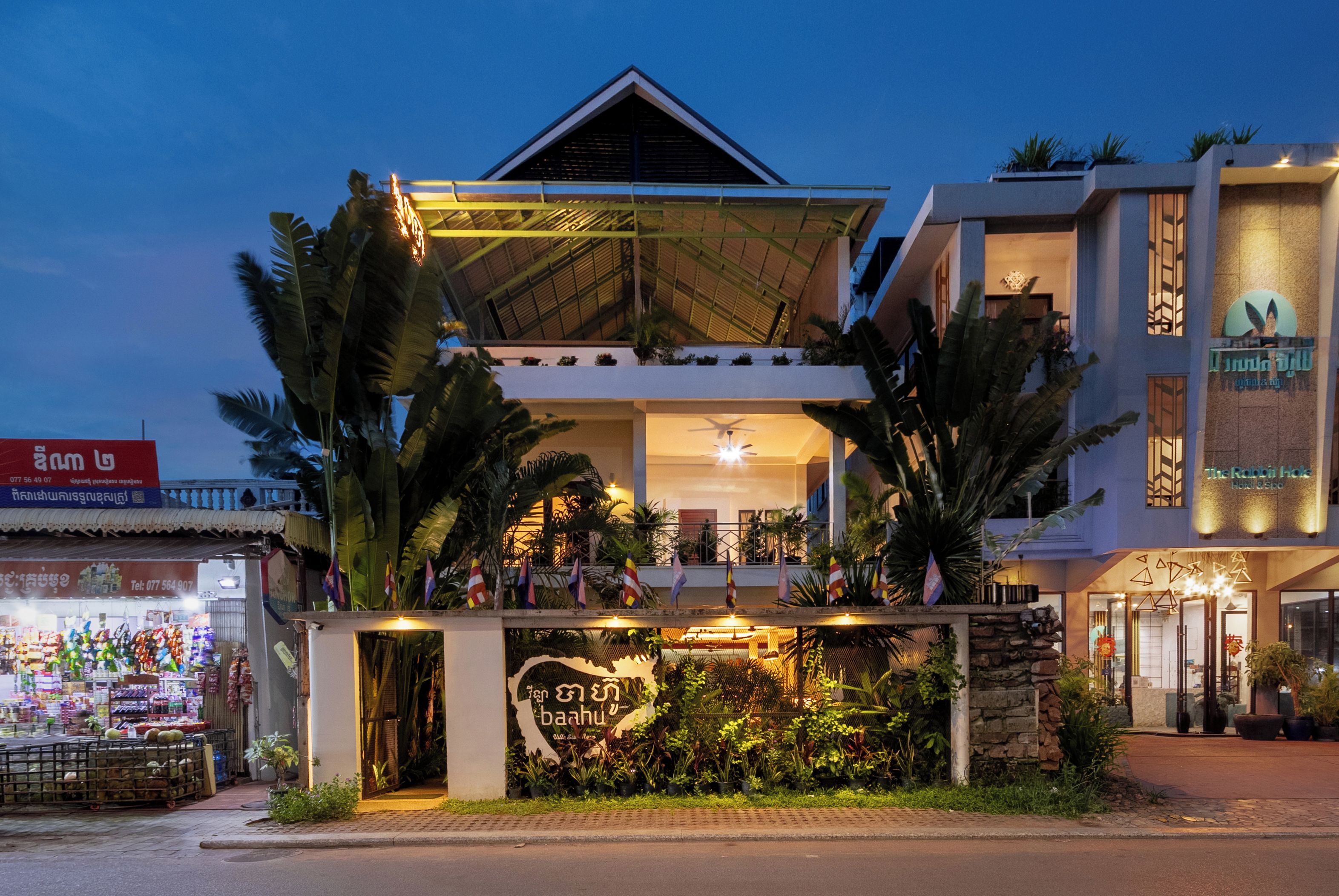 A hotel with a prominent balcony and a sign with Thai script.